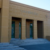 A view towards the pillared entrance of a yellow sandstone Council Chambers building  