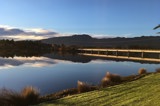 View towards a road bridge over a river with mountain range in the background