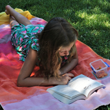 Girl lying on picnic blanket reading